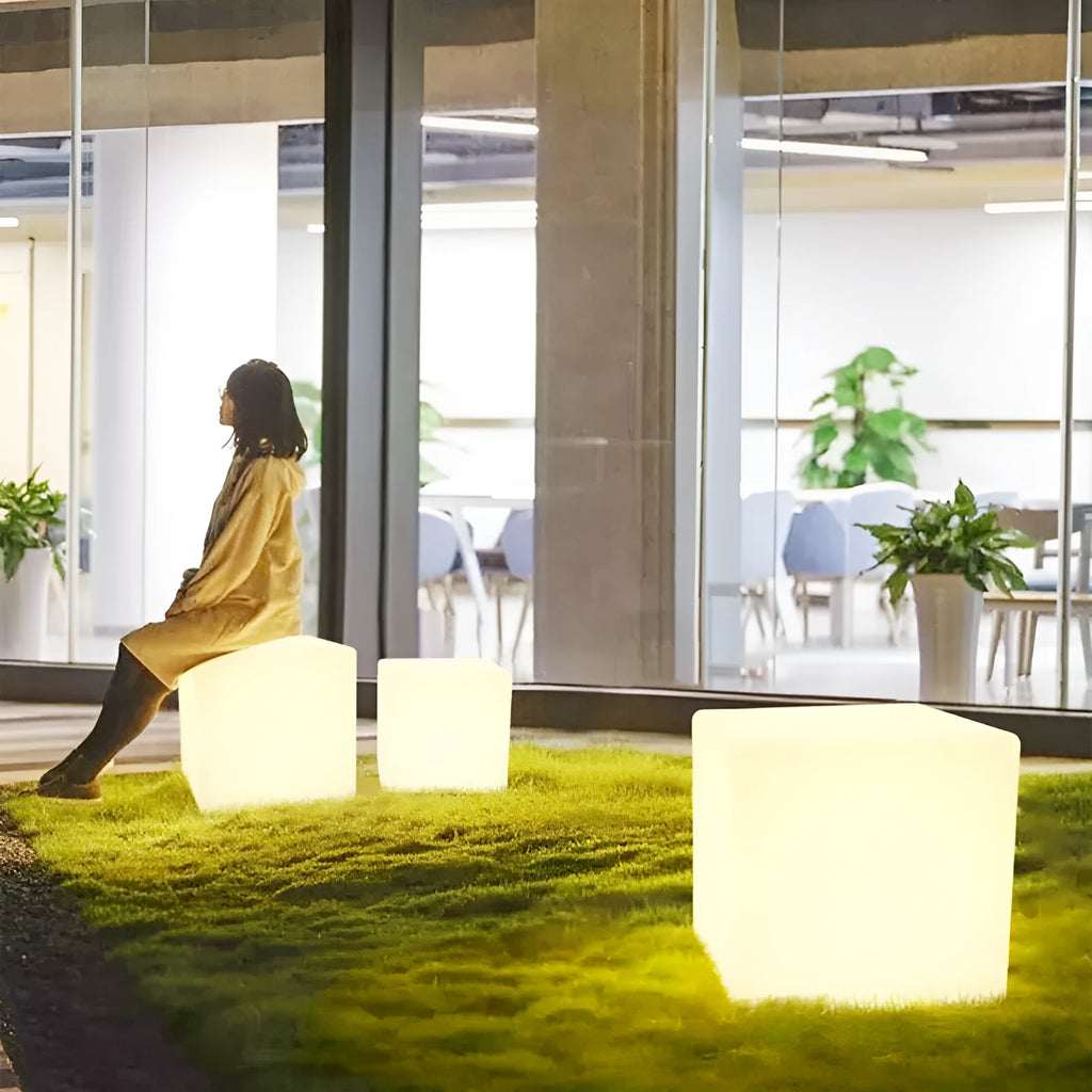 White square LED cube stool light for outdoor use, showing modern design with solar panel or charging port.