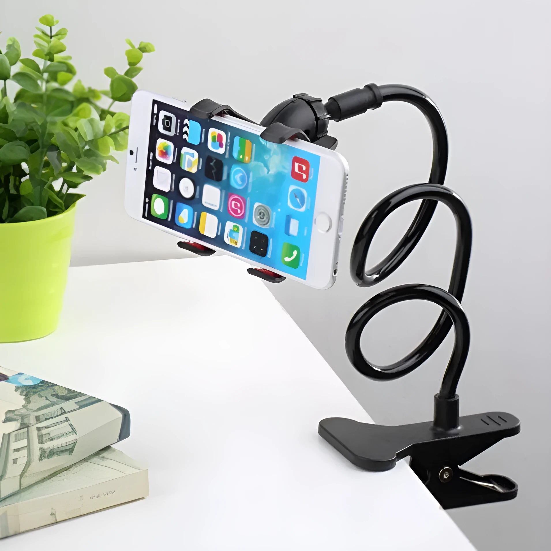 Black flexible long arm phone holder with V-clip attached to a bed frame, holding a smartphone.