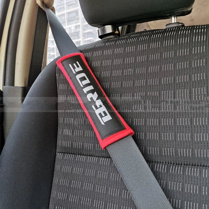 Pair of black car seat belt shoulder pads made from cotton and sponge cloth, showing size and embroidery detail.