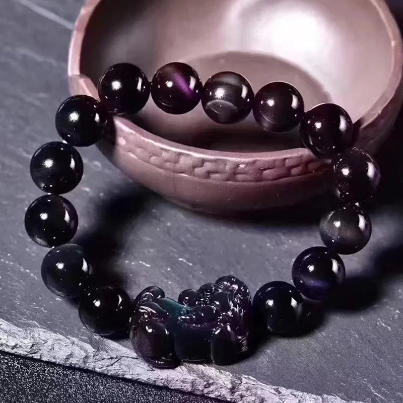 Natural obsidian stone bead bracelet with adjustable black cord on a wrist.