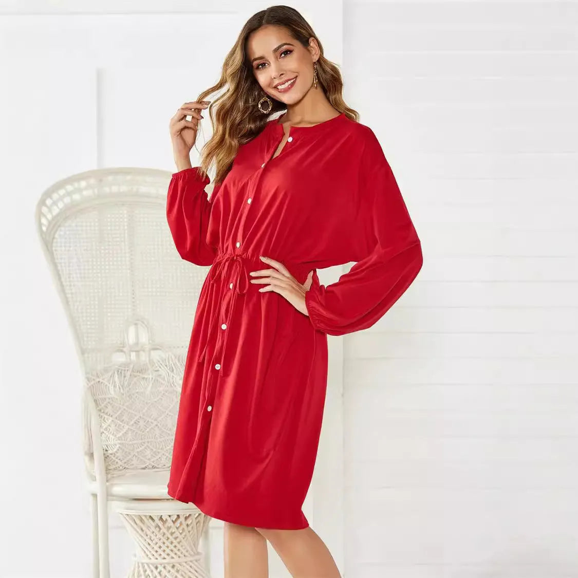 A woman wearing a solid colour midi dress with an elastic waist, long sleeves, and a loose belt.