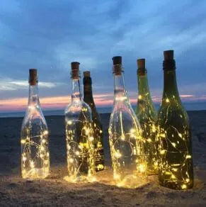 Silver copper wire LED string lights wrapped around a wine bottle with bottle stopper