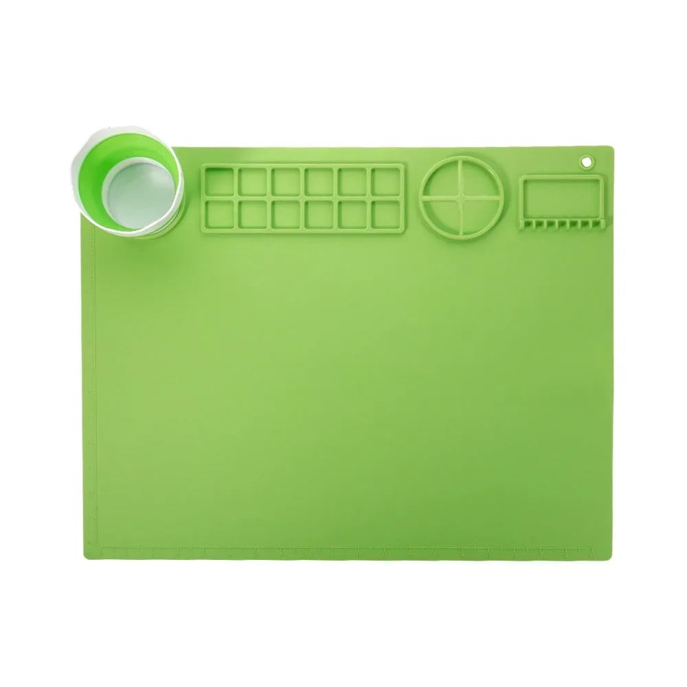 Green silicone painting mat measuring 50 by 40 centimetres with two round bowl wells for holding water or paint.