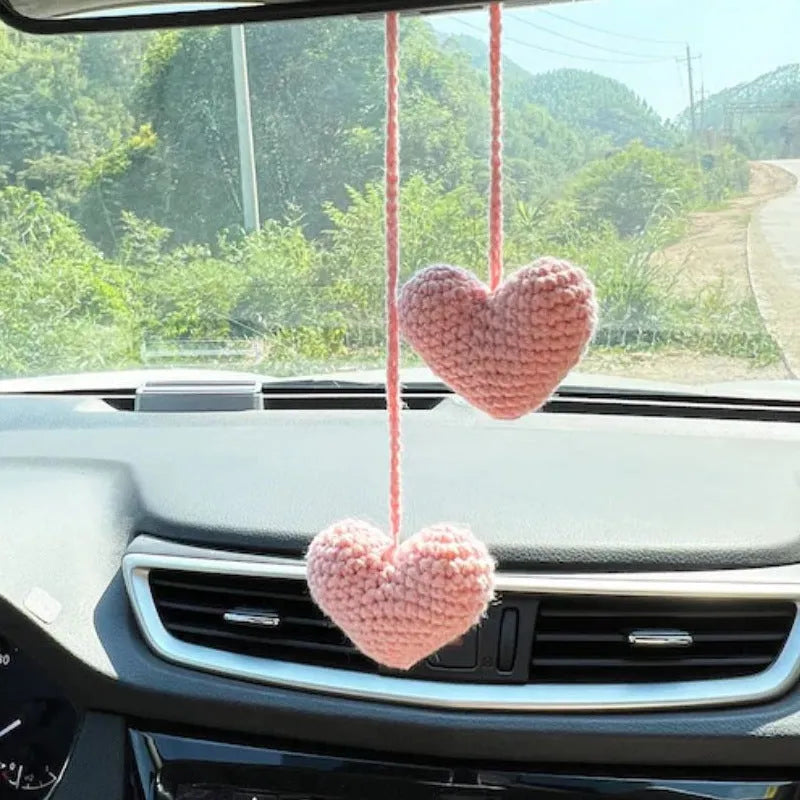 Green and white knitted wool car plant decoration with hanging rope on car dashboard