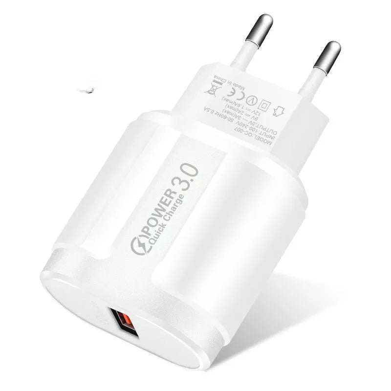 Compact white international travel phone charger with UK, US, and EU plug adapters on a desk