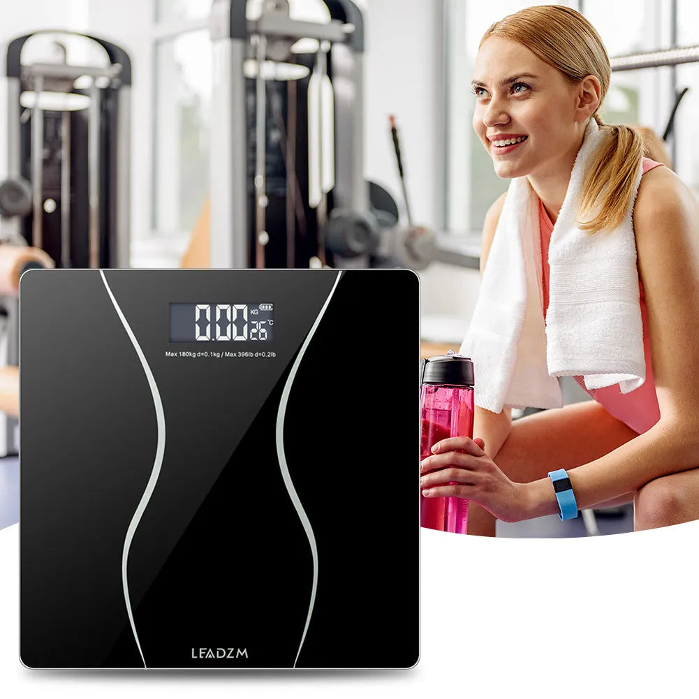 Black electronic digital bathroom scale on a tiled floor showing weight display.