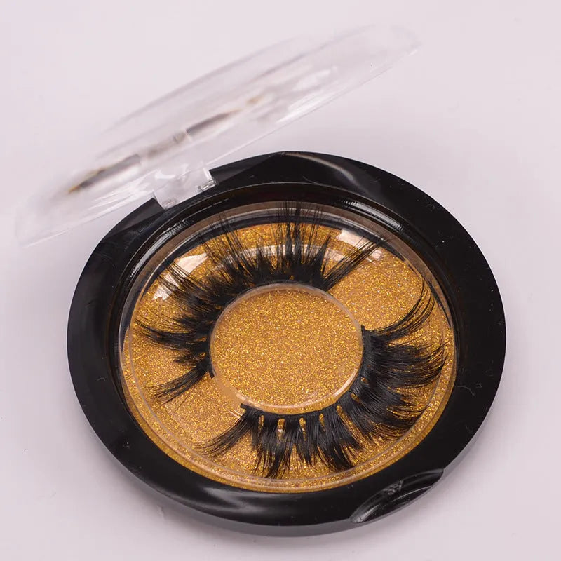 A pair of 5D style false eyelashes made from mink hair, shown with a double-headed brush and a black hair cap.