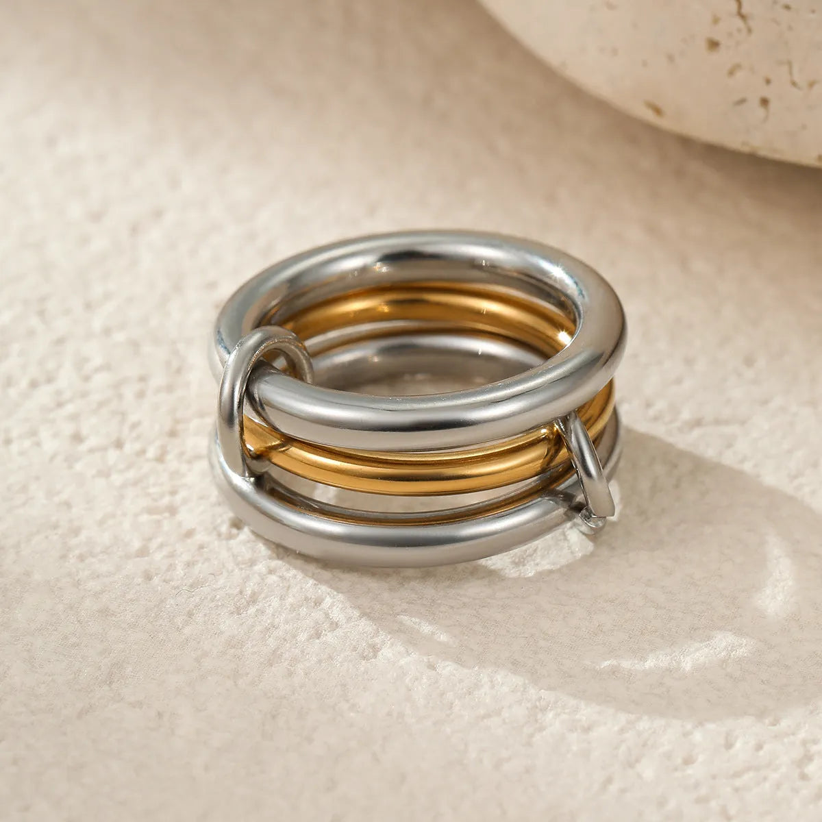 Stacked gold plated stainless steel ring set showing exaggerated design on a model's hand.