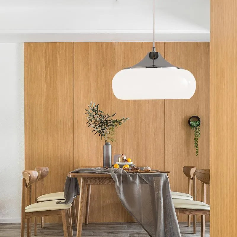 Three-headed Bauhaus pendant light with milky white glass egg tart shades hanging from a ceiling.