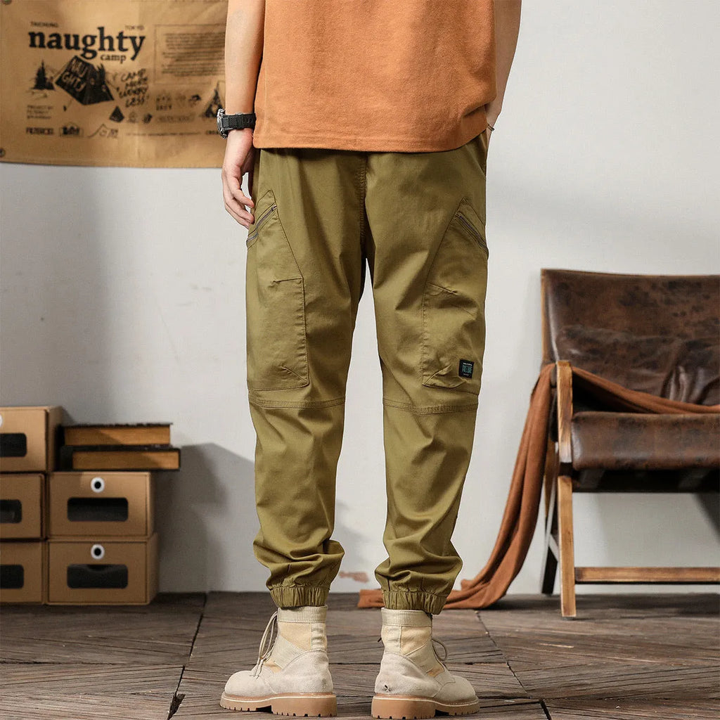 Men's khaki cotton tapered harem pants with an ankle band and loose fit.