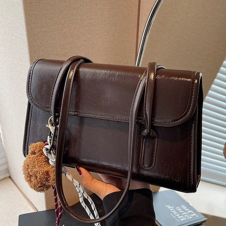 Brown women's structured square PU leather shoulder bag with a detachable tassel pendant and double straps.