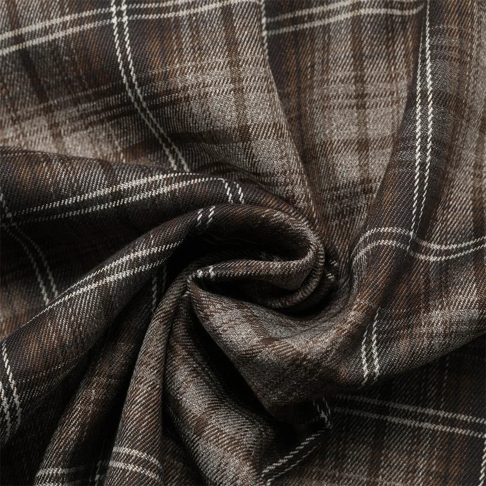 Man wearing a black and brown plaid short sleeve shirt with embroidered letters on the lapel