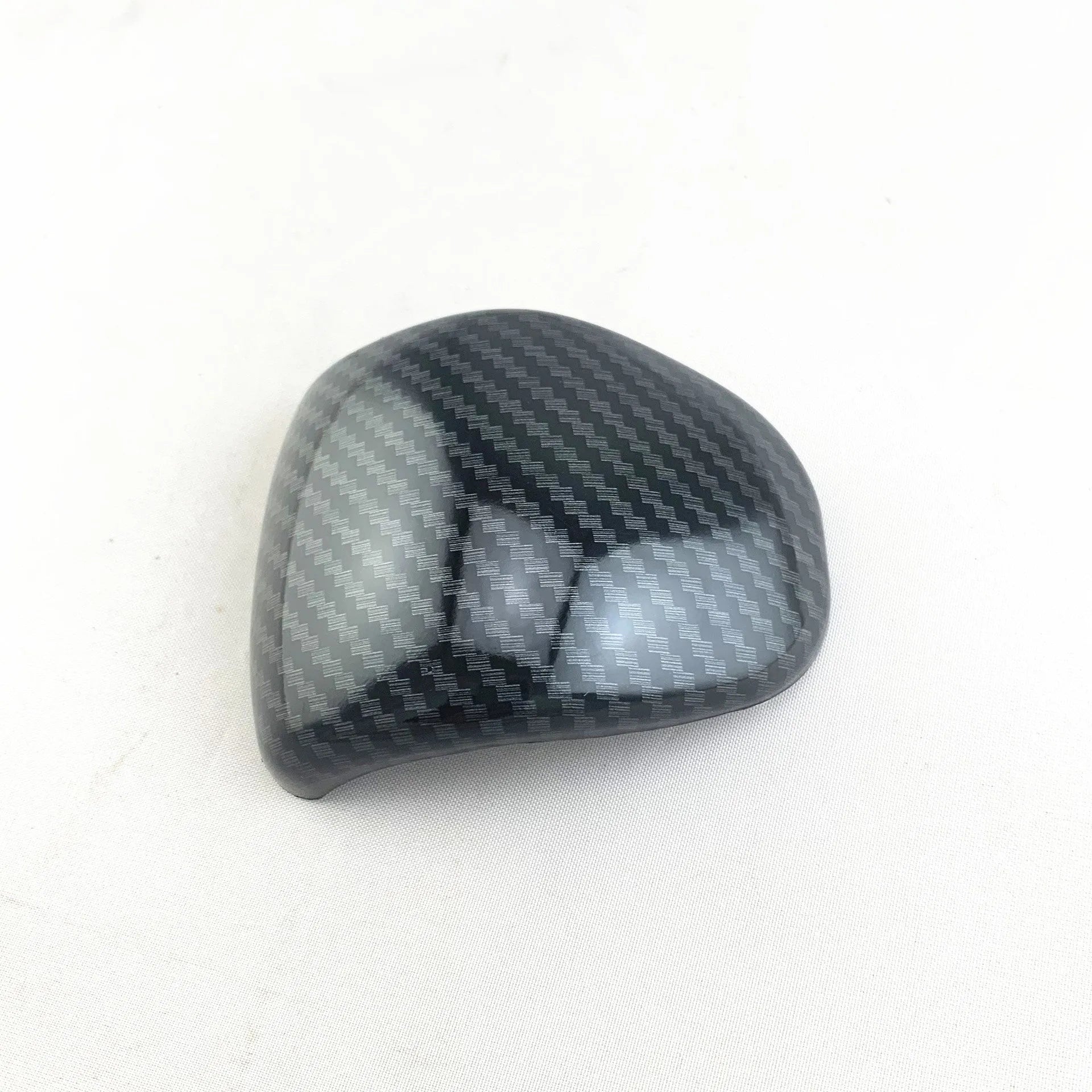 Black gear shift cover with a carbon fibre pattern for car interior styling.