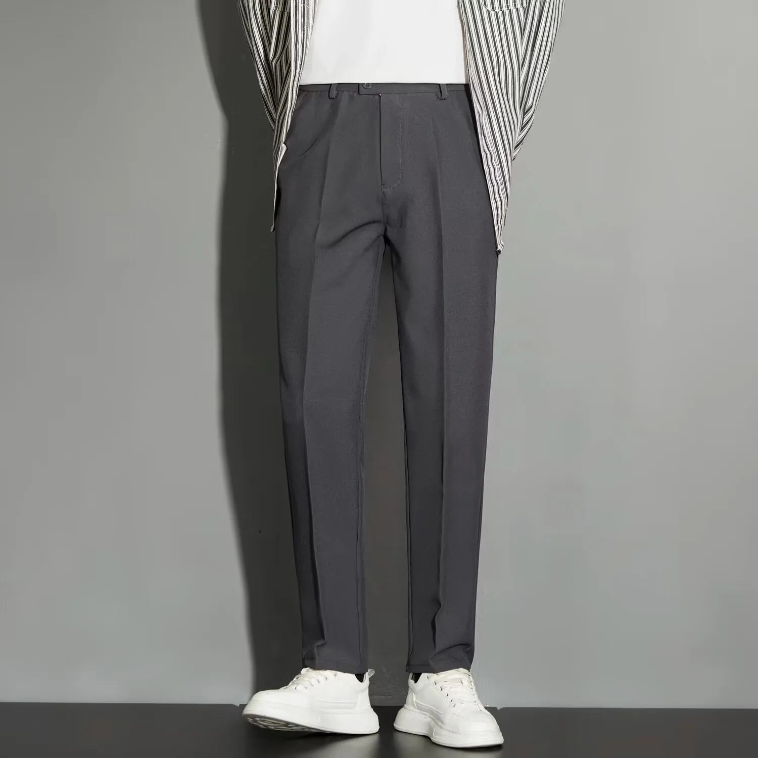 Man wearing straight leg ankle-length suit trousers in a light colour, showing the drape of the fabric.