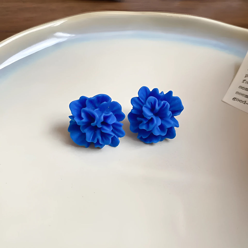 Women's geometric blue and silver fabric drop earrings with a resin flower detail.