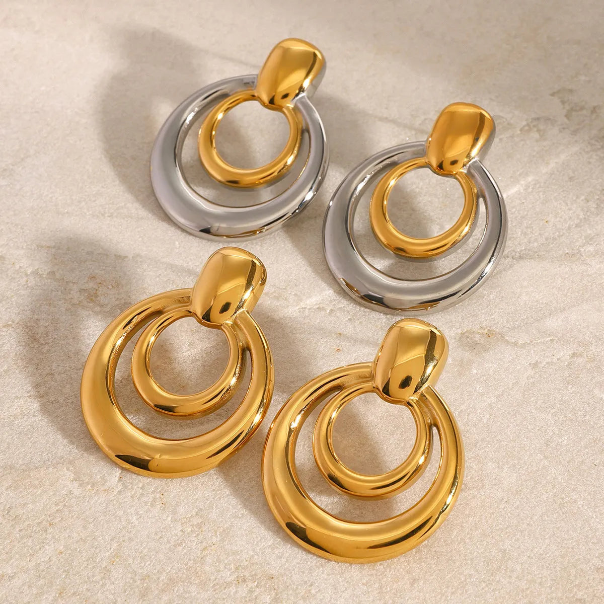 Round double layer hollow stud earrings with a gold electroplated finish on a titanium steel base.