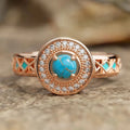 Close-up of a women's rose gold turquoise ring with geometric inlaid zircon stones on a copper band.