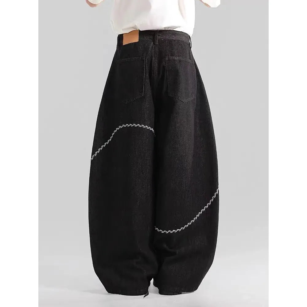 Men's black straight-leg denim trousers with a zip fly on a mid waist, shown in a casual street style.