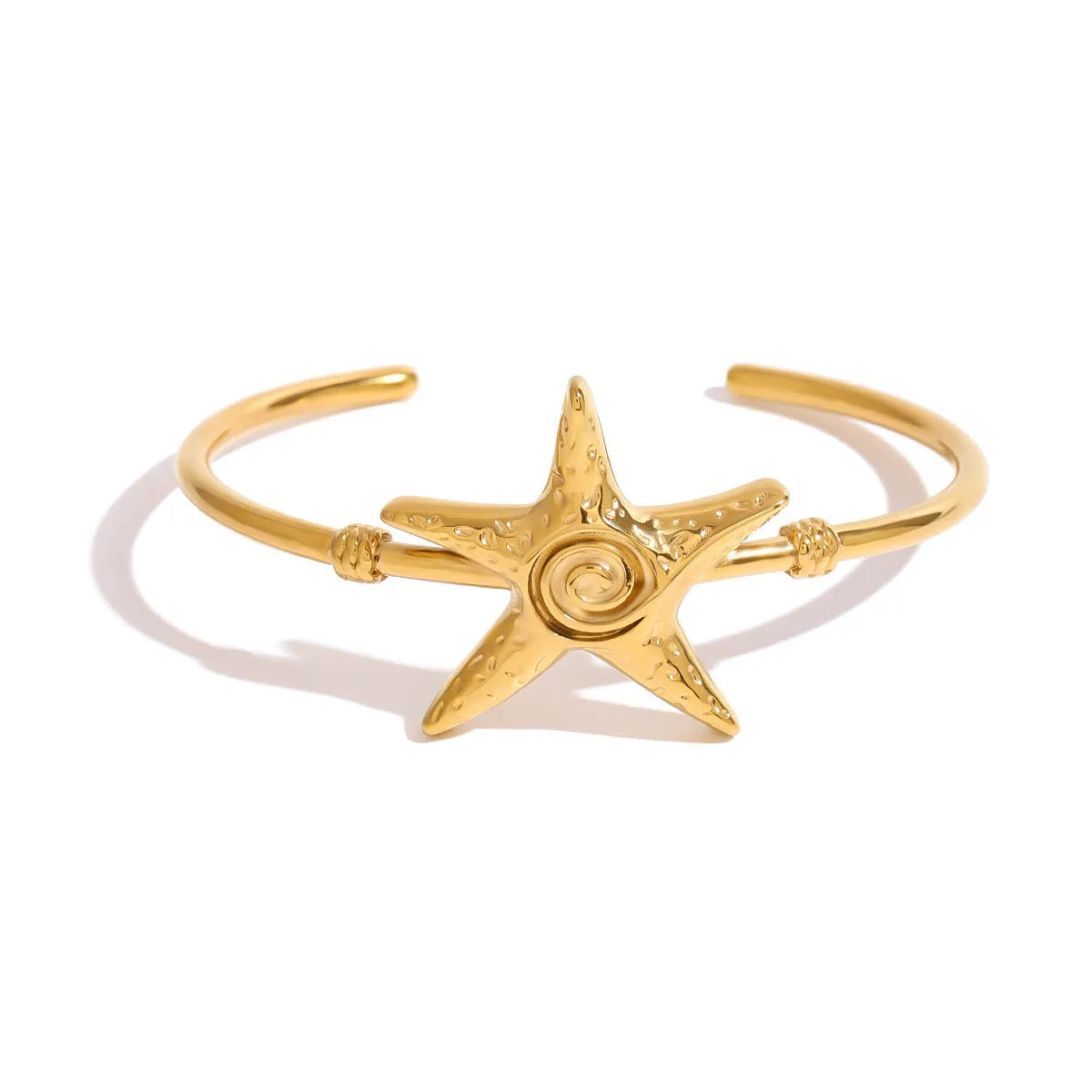 Stainless steel open-ended bracelet with starfish charm on a flat surface