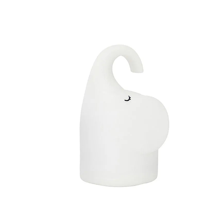 DOMI soft silicone elephant night light on a bedside table emitting warm white glow