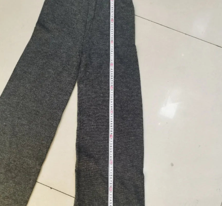 Women's dark grey knit co-ord suit with side-slit sweater and matching trousers laid flat.