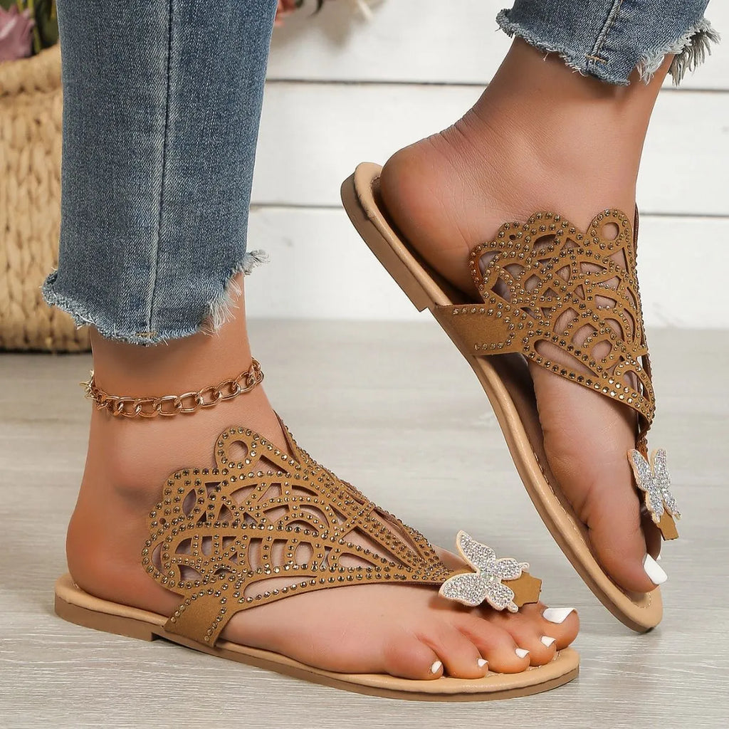 Women's black slip-on sandals with rhinestone decoration on the flip-toe and a flat rubber sole.