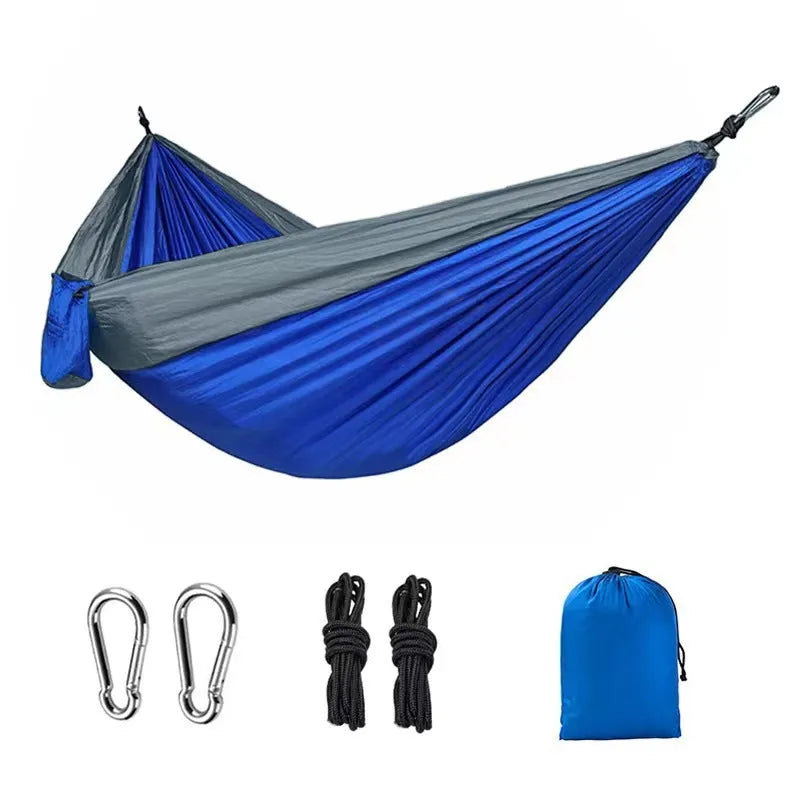 Blue parachute nylon camping hammock hanging between trees with 300kg capacity