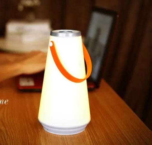 White rechargeable LED bedside night light with adjustable warm glow on wooden table
