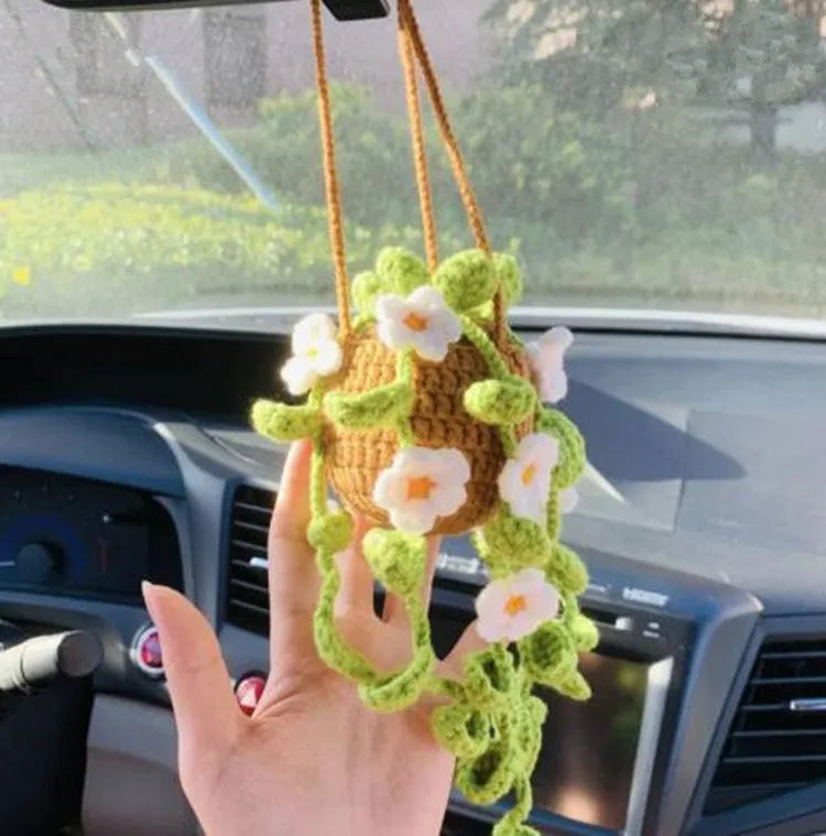 Green and white knitted wool car plant decoration with hanging rope on car dashboard