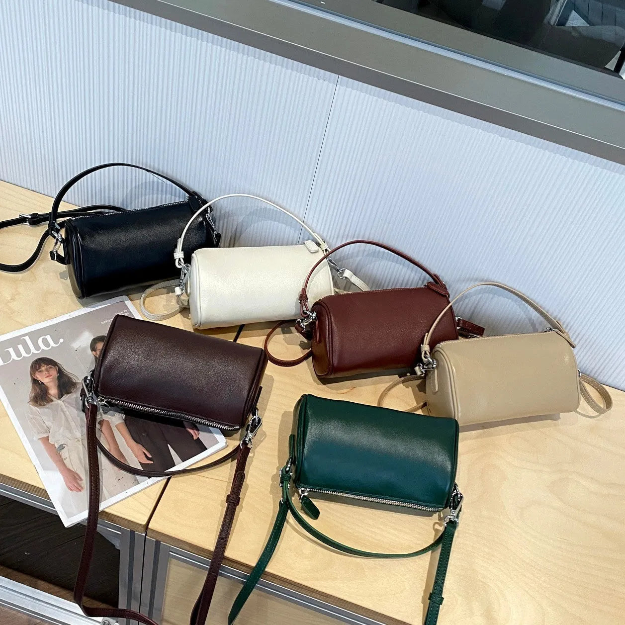 Soft genuine leather cylindrical crossbody bag for mobile phones, shown in a street style with visible stitching.