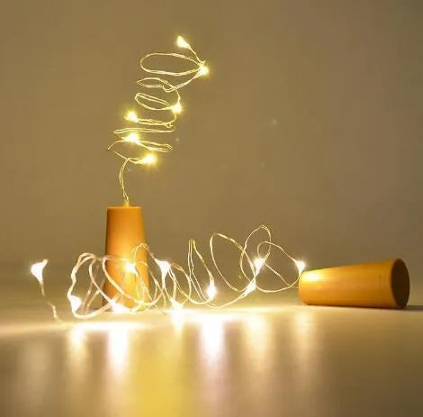 Silver copper wire LED string lights wrapped around a wine bottle with bottle stopper