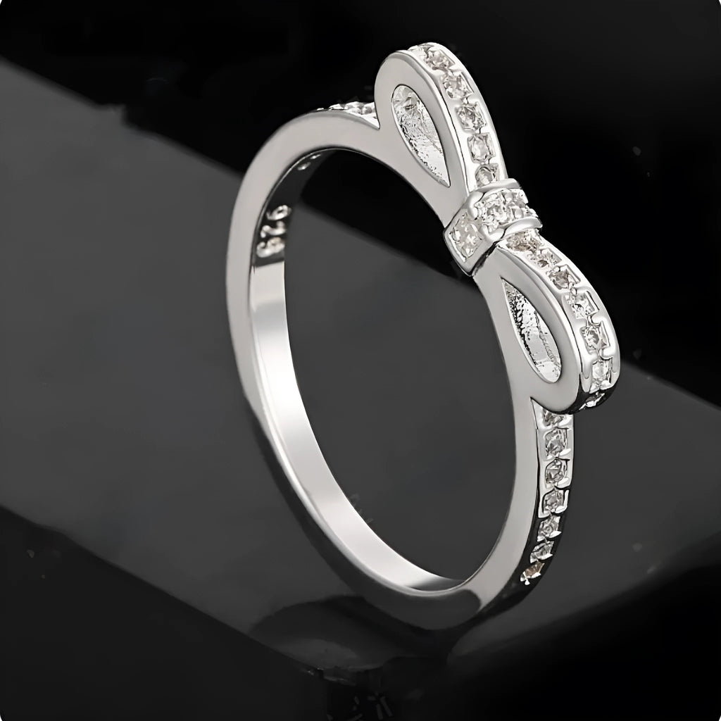 Silver couple style ring with a rhinestone and zircon crystal bow design on a finger.