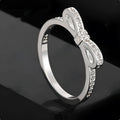Silver couple style ring with a rhinestone and zircon crystal bow design on a finger.
