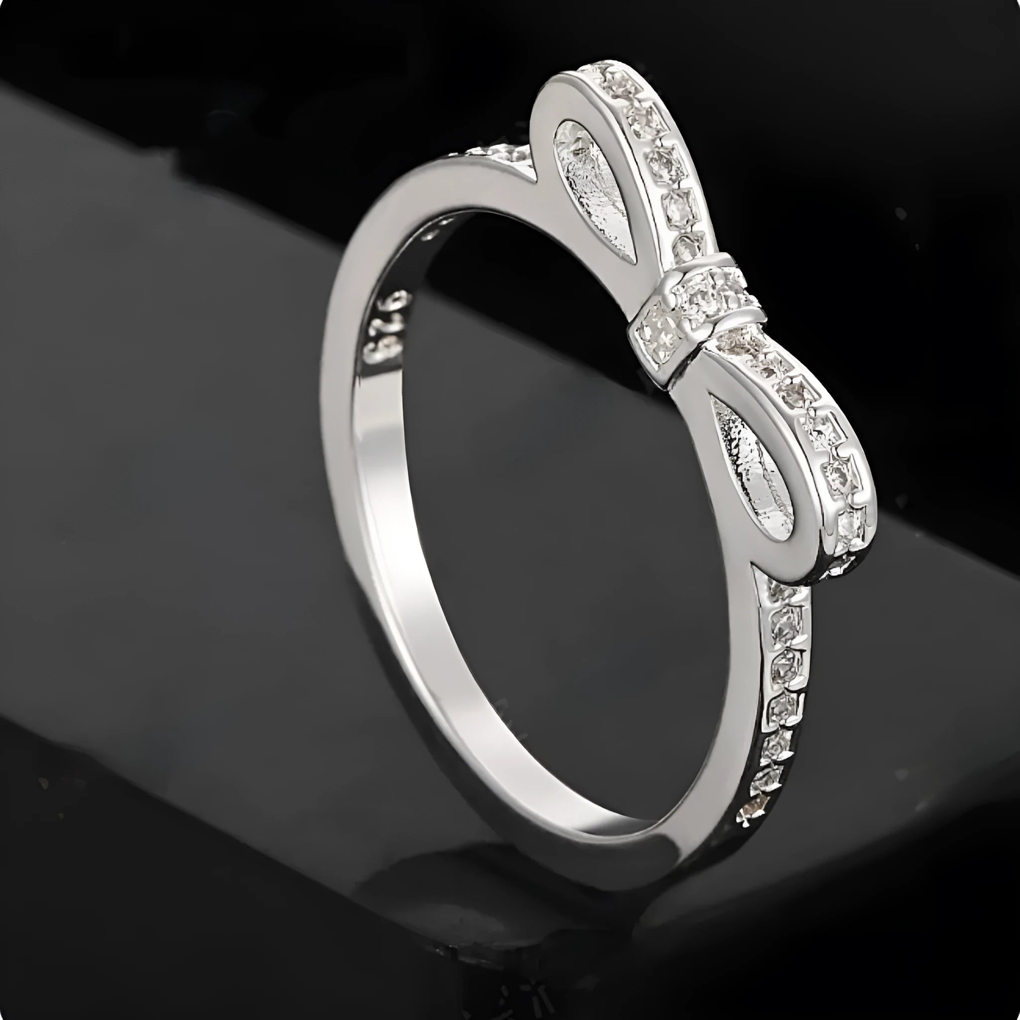 Silver couple style ring with a rhinestone and zircon crystal bow design on a finger.