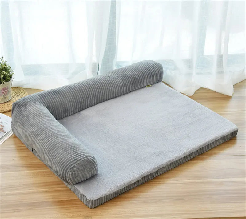 Corduroy dog sofa bed in grey, showing high sides and non-slip base, placed on a wooden floor.
