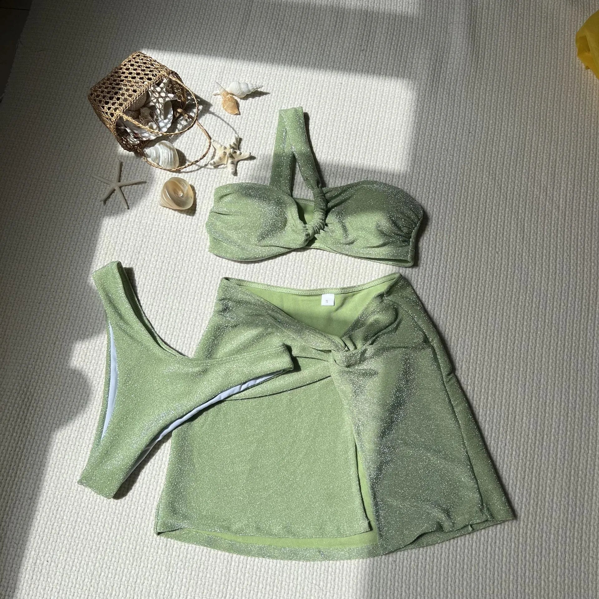 Light green one-shoulder tube top swimsuit three-piece set with matching skirt on a mannequin.