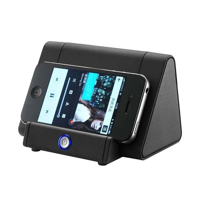 Small black and white wireless Bluetooth speaker with built-in USB charging cable on a desk.