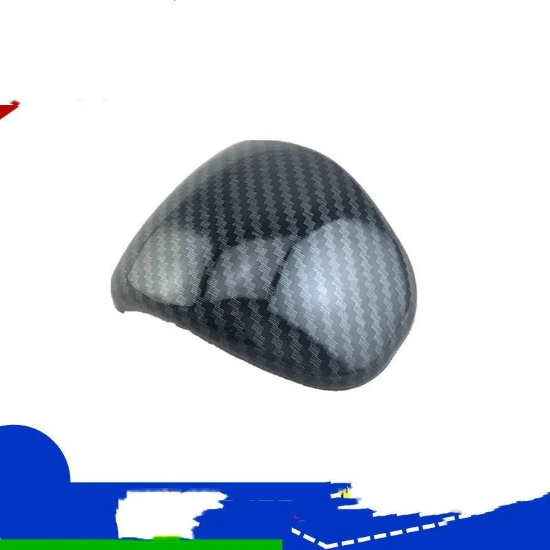 Black gear shift cover with a carbon fibre pattern for car interior styling.