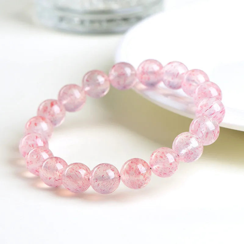 Natural strawberry quartz crystal bracelet with 19 round geometry beads on a white background.
