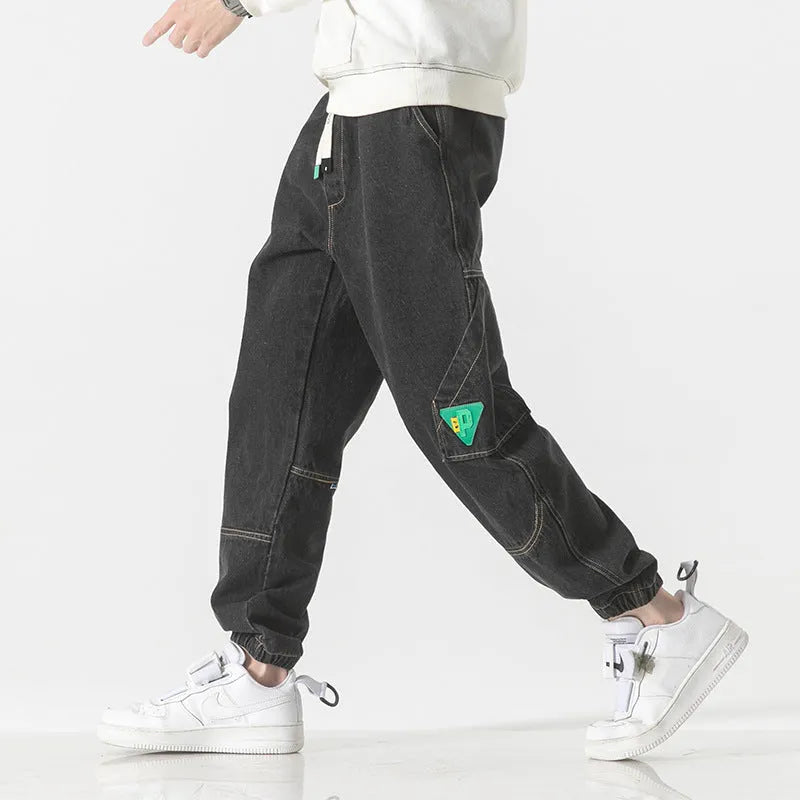 Men's loose fit tapered cotton trousers in black, shown on a model, featuring a mid-waist and tapered leg design.