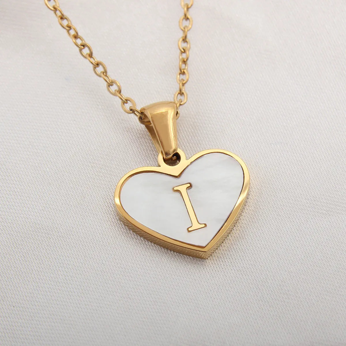 Gold-plated heart necklace with white shell pendant personalised with a letter, on an adjustable chain.