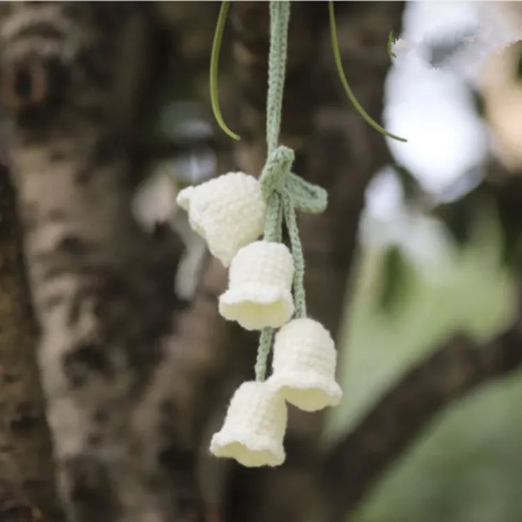 Green and white knitted wool car plant decoration with hanging rope on car dashboard