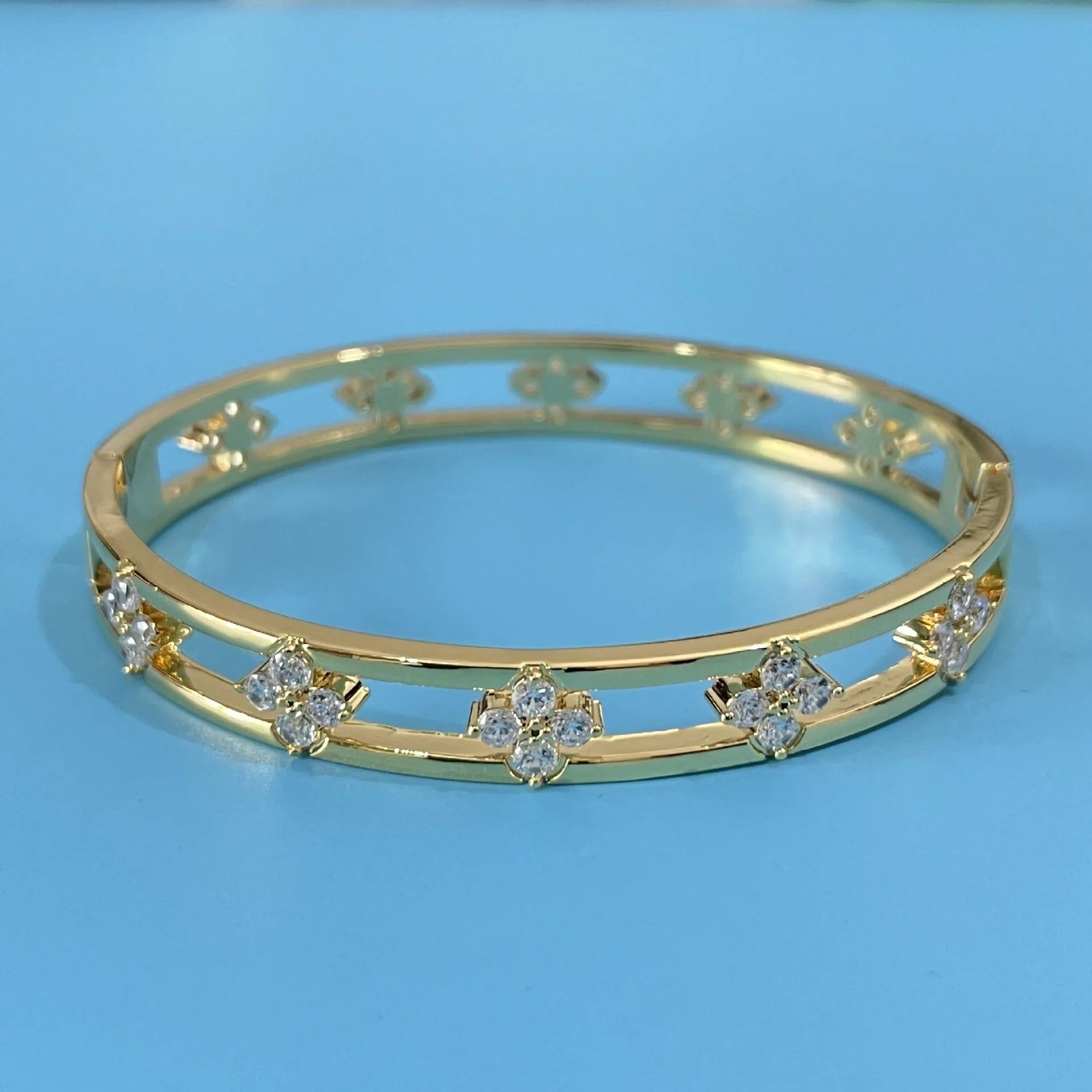Gold or silver adjustable hollow bracelet with a four-leaf clover charm inlaid with a zircon stone.