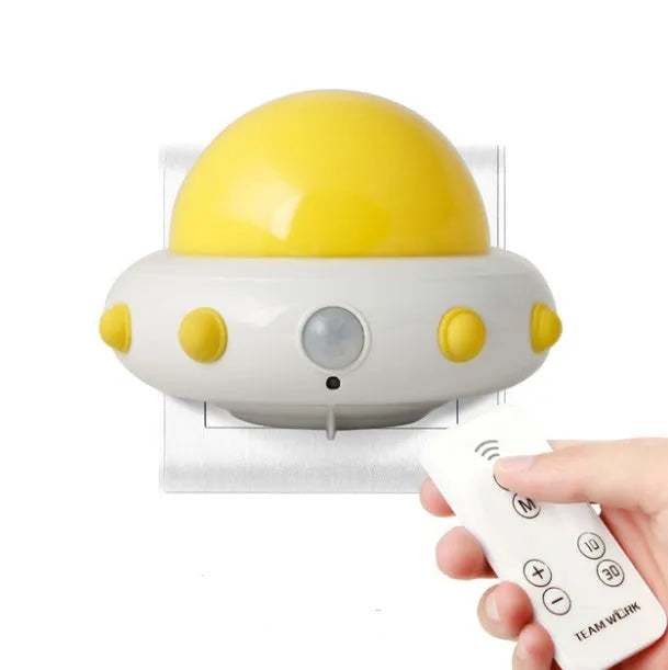 Blue UFO-shaped bedside night light with remote control on a table.