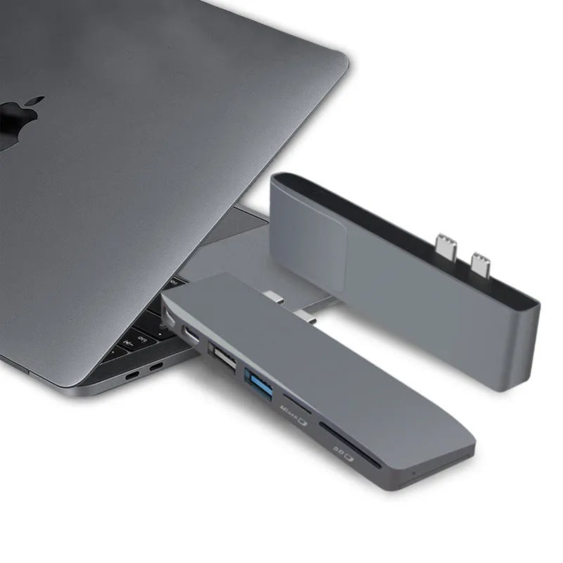 Silver USB-C multi-port hub for MacBook Pro with eight interface ports including USB, card slots, and display output
