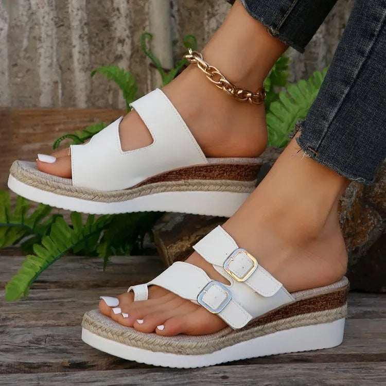 White patent leather wedge sandals with woven finger fit design and peep toe on a rubber sole.