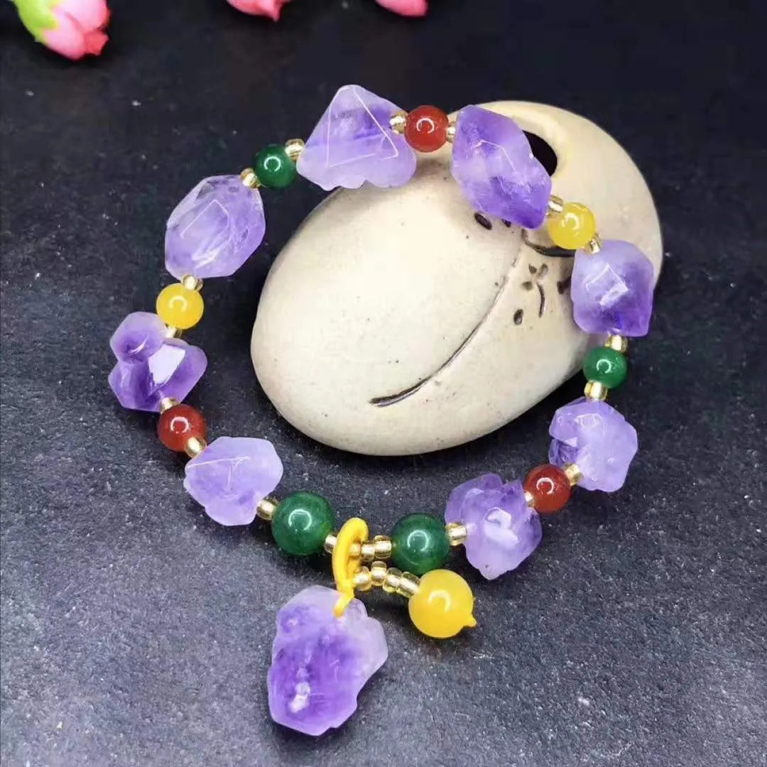 Close-up of a purple natural amethyst bead bracelet with a fu charm for women, on a white background.