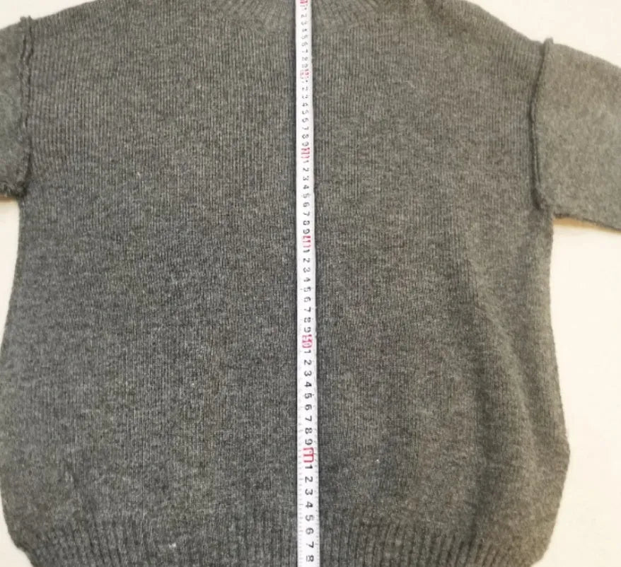 Women's dark grey knit co-ord suit with side-slit sweater and matching trousers laid flat.