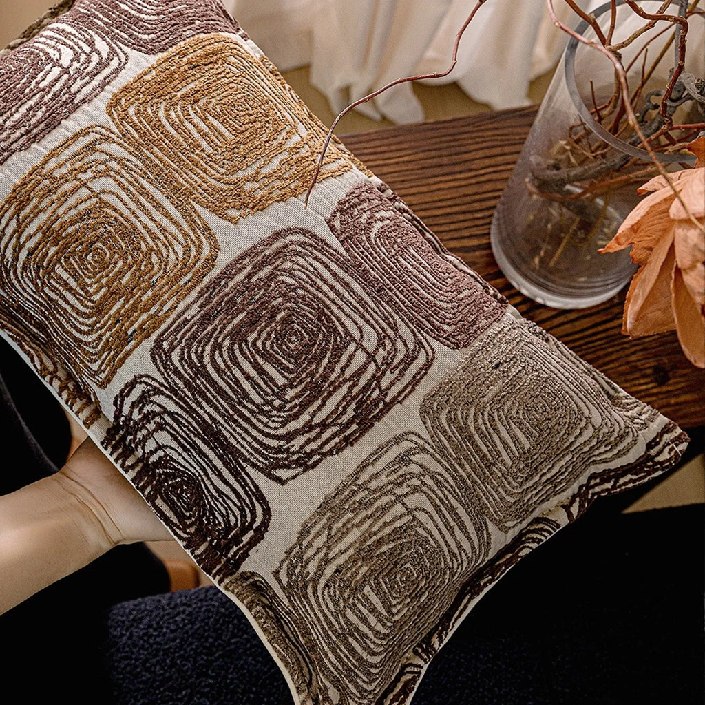 Cream and coffee coloured abstract coil pattern on two pillow sizes: a square cushion and a rectangular bolster.