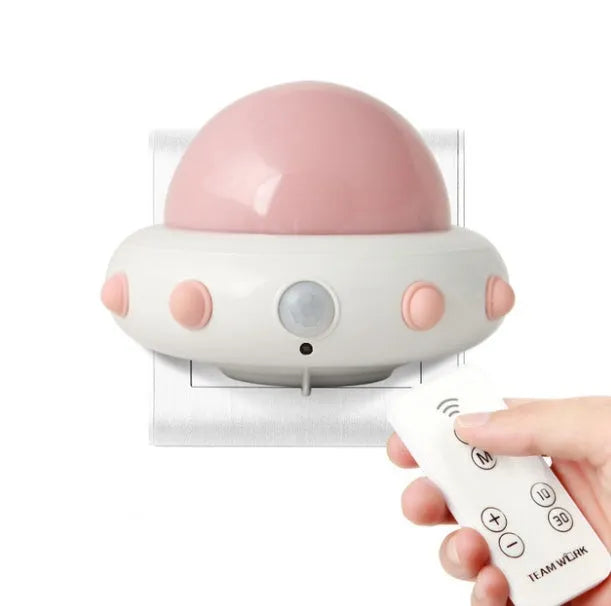 Blue UFO-shaped bedside night light with remote control on a table.